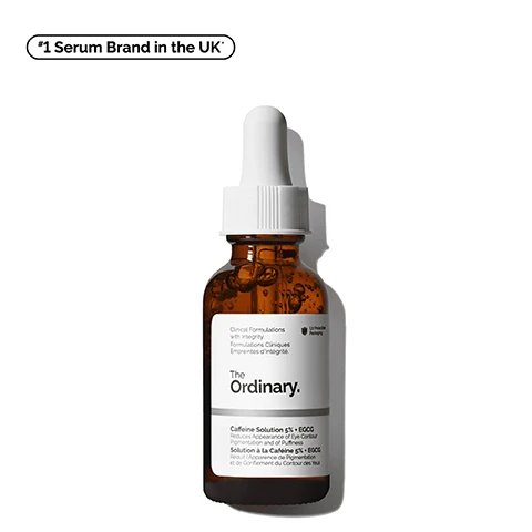 Image 1 - A brown glass bottle with a dropper lid contains a serum labeled The Ordinary Caffeine Solution 5% + EGCG, with text indicating it reduces the appearance of eye contour pigmentation and puffiness, along with a note showing it as the #1 Serum Brand in the UK.
Image 2 - A close-up image of a golden liquid flowing from a transparent bottle with text beside it listing benefits: reduces the look of puffiness, reduces the look of dark circles, improves the look of skin luminosity.
Image 3 - A close-up of a person applying a skincare product under their eye, showing healthy skin, with text labels for Depuffing and Brightening visibly displayed.
Image 4 - Close-up of a translucent gel with bubbles, labeled with key ingredients for Caffeine Solution 5% + EGCG, including descriptions for Caffeine and Epigallocatechin gallatyl glucoside (EGCG).
Image 5 - An image displaying a skincare regimen with three products labeled as PREP, TREAT, and SEAL, including Squalane Cleanser, Caffeine Solution 5% + EGCG, Ascorbyl Glucoside Solution 12%, and Natural Moisturizing Factors + HA, with descriptions for each product detailing their benefits for brighter skin.