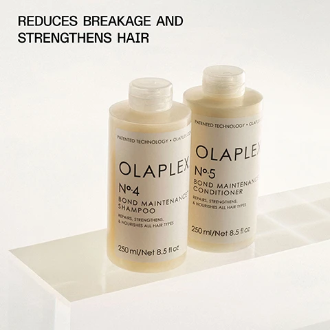 Image 1 - Two bottles of OLAPLEX hair care products are displayed on a white surface, with the labels reading Olaplex No. 4 Bond Maintenance Shampoo and Olaplex No. 5 Bond Maintenance Conditioner, accompanied by the text Reduces breakage and strengthens hair.
Image 2 - Two bottles of OLAPLEX shampoo and conditioner with bubbles on a light background, featuring the text THE #1 PRESTIGE SHAMPOO & CONDITIONER* and information about the product.
Image 3 - A close-up portrait of a person with long, straight black hair partially covering their face, wearing a white shirt with red stripes, against a light beige background, with the text STRENGTHEN, MOISTURIZE, AND REPAIR ALL HAIR TYPES displayed above.