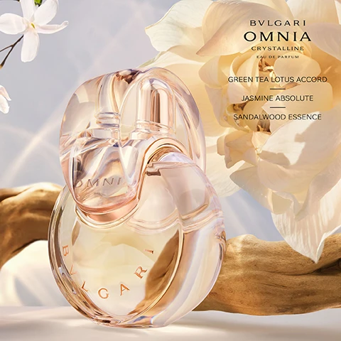 Image 3 - A clear, interlocked perfume bottle with light amber liquid, labeled Bvlgari Omnia Crystalline, rests on a piece of driftwood against a background of soft white and cream flowers, with the visible text BVLGARI OMNIA CRYSTALLINE EAU DE PARFUM GREEN TEA LOTUS ACCORD JASMINE ABSOLUTE SANDALWOOD ESSENCE. Image 4 - Two hands cupped together hold a pile of small white jasmine flowers, with the text JASMINE ABSOLUTE FROM FLOWER GEMS OF INDIA PROGRAM THIS PROJECT AIMS TO PRODUCE SUSTAINABLE HIGH QUALITY JASMINE ABSOLUTE, LEVERAGE PERMACULTURE PRINCIPLES AND MAKE JASMINE PRODUCTION PROFITABLE AND ATTRACTIVE FOR FUTURE GENERATION. Image 6 - An advertising image shows two Bvlgari Omnia Crystalline perfume bottles, a clear one labeled Eau de Toilette and a light amber one labeled Eau de Parfum, against a background of white flower petals, driftwood, and a melon slice, with prominent text reading Bvlgari Omnia Crystalline, Eau de Toilette Radiant Crispy, and Eau de Parfum Graceful Enveloping. Image 7 - Four Bvlgari Omnia perfume bottles are displayed, each in a column with corresponding visual elements and descriptive text: a red bottle with hibiscus flowers and a red background for BVLGARI OMNIA CORAL EAU DE TOILETTE FLORAL FRUITY JUICY LIVELY; a clear bottle with lotus flowers and a white background for BVLGARI OMNIA CRYSTALLINE EAU DE TOILETTE FLORAL WOODY RADIANT CRISPY; a golden bottle with jasmine flowers and a light background for BVLGARI OMNIA CRYSTALLINE EAU DE PARFUM FLORAL WOODY GRACEFUL ENVELOPING; and a purple bottle with amethyst flowers and a purple background for BVLGARI OMNIA AMETHYSTE EAU DE TOILETTE FLORAL FLORAL DELICATE POWDERY.
