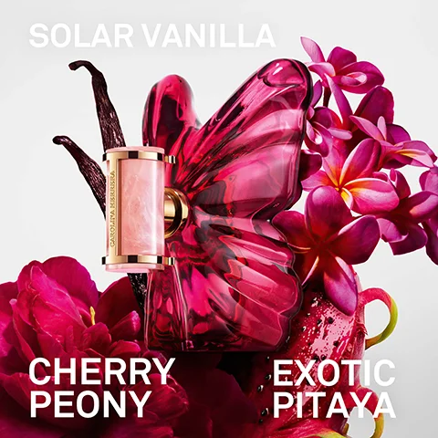 A pink butterfly-shaped perfume bottle with a small rectangular applicator, accompanied by vanilla beans, pink peonies, plumeria flowers, and a cut dragon fruit, with the text SOLAR VANILLA, CAROLINA HERRERA, CHERRY PEONY, EXOTIC PITAYA.