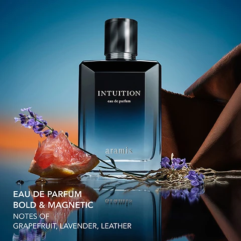 Image 1 - A dark blue and black Intuition eau de parfum bottle by Aramis is shown on a reflective surface with a slice of grapefruit, lavender sprigs, and brown fabric, with visible text reading INTUITION eau de parfum aramis EAU DE PARFUM BOLD & MAGNETIC NOTES OF GRAPEFRUIT, LAVENDER, LEATHER. Image 2 - A man with a beard wearing a dark suit stands against a blue background, with a dark and blue cologne bottle in the foreground, and text that reads Ask yourself...and listen. INTUITION eau de parfum aramis Starring DWYANE WADE. Image 3 - A close-up of textured dark brown fabric, possibly leather or suede, with text overlay that reads: WARM & ADDICTIVE, CUIRISSIMA LXR, EXCLUSIVE ARAMIS ESSENCE. Image 4 - A close-up of a pink grapefruit, partially peeled to reveal glistening segments, with a few water droplets on the peel and the text CRISP & INVIGORATING GRAPEFRUIT. Image 5 - Lavender flowers against a blue background with the text Fresh & Energizing Lavender. Image 6 - Close-up of dried, light brown woody roots or branches against a deep blue background with the white text Woody & Evocative Vetiver.
